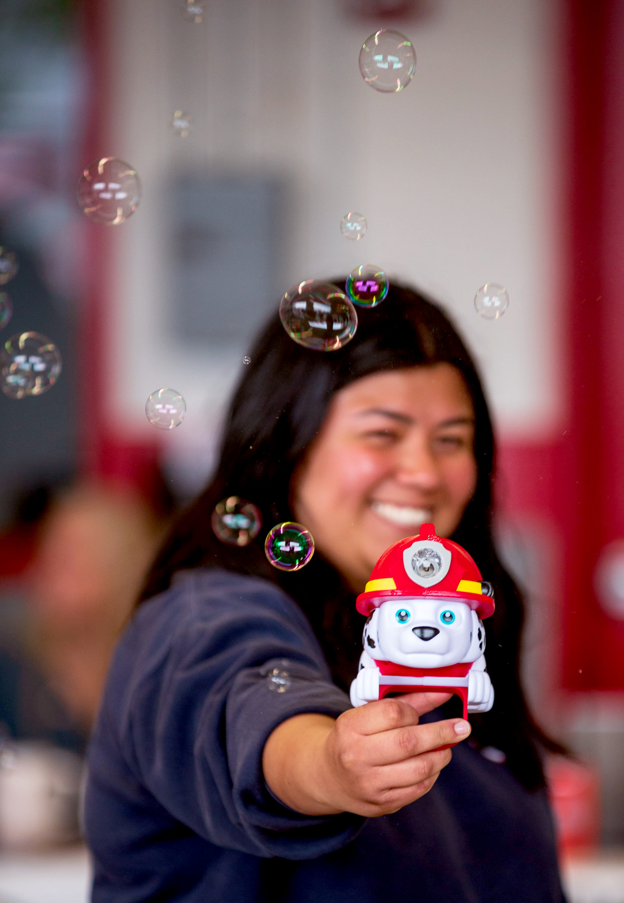 Firefighter Viancka Lopez Smiles As She Makes Bubble With A Dalmatian Toy.